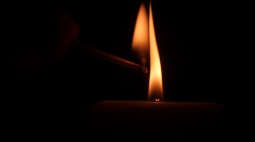 Close-up of lit candle in darkroom