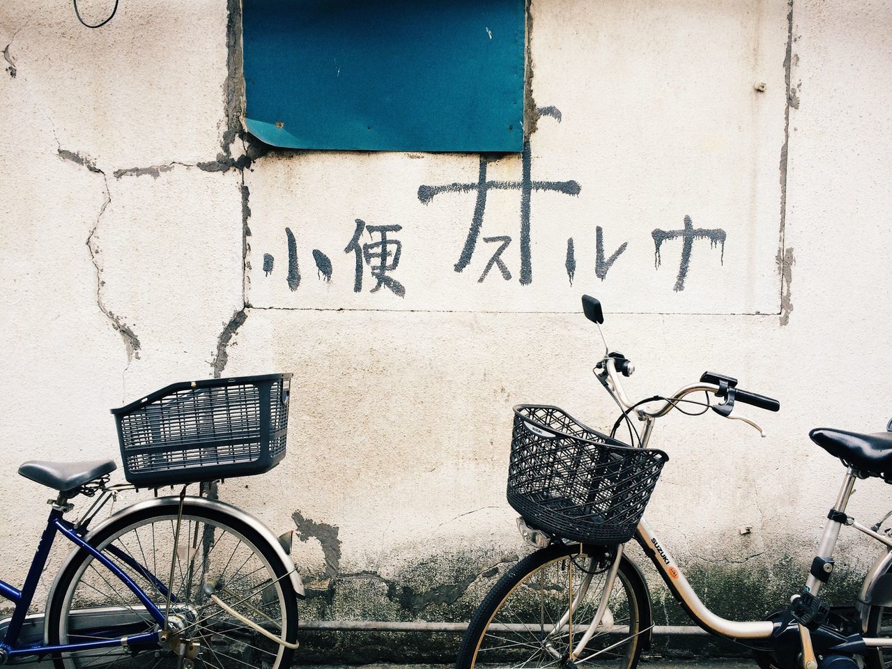 bicycle, transportation, stationary, land vehicle, parking, parked, mode of transport, wall - building feature, built structure, architecture, text, wall, building exterior, western script, graffiti, day, communication, outdoors, no people, street