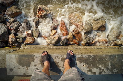 Low section of man standing by water