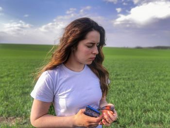 Young woman using mobile phone on field