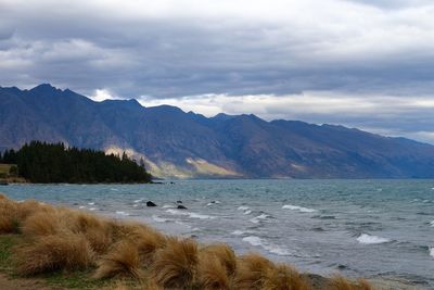 Scenic view of sea and mountains against sky