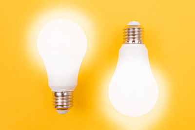 Close-up of illuminated light bulb against yellow background