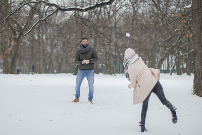 Happy couple playing on snow covered land during winter