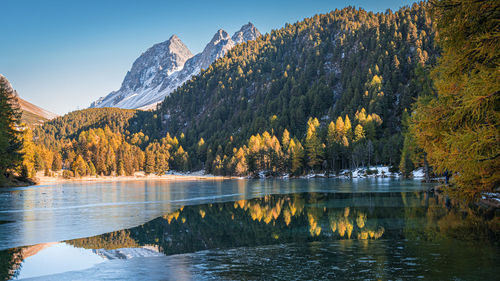 Scenic view of half frozen lake in autumn and mountains against sky