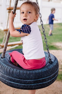 Child swinging on the rings, swings from wheels on playground. girl having fun during walk. 