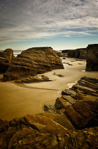 Scenic view of rocks on shore against sky