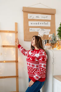 Portrait of young woman standing against wall