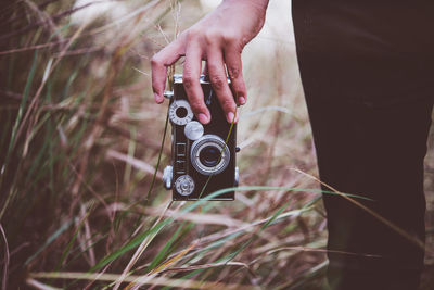 Midsection of woman holding camera on field