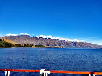 Scenic view of lake and mountains against blue sky