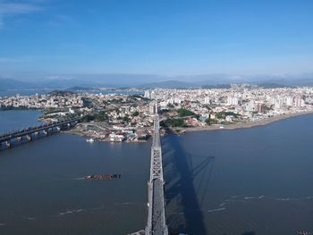 High angle view of city by sea against blue sky