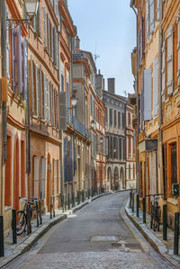 Empty road amidst buildings in city