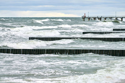 Scenic view of blue sea with foaming waves. vintage long wooden breakwaters in sea