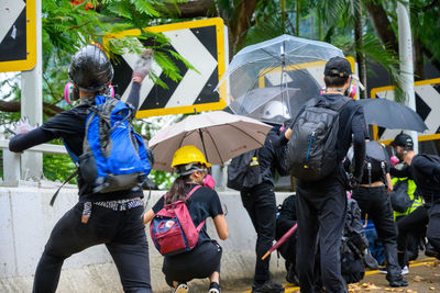 Rear view of people walking on street in rain