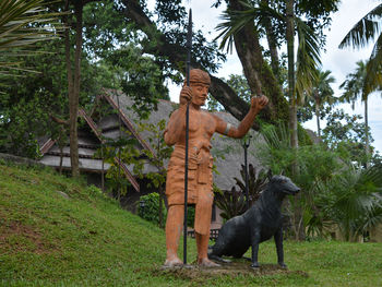 Statue by palm trees against sky