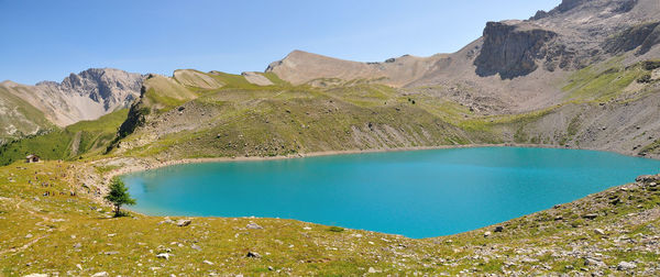 Scenic view of lake by mountains against blue sky