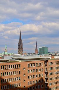 Buildings in city against cloudy sky