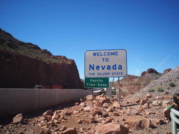 Information sign on rocks against clear blue sky