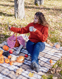 Leisure, free time. beautiful caucasian woman in red sweater on a picnic outdoors, sitting