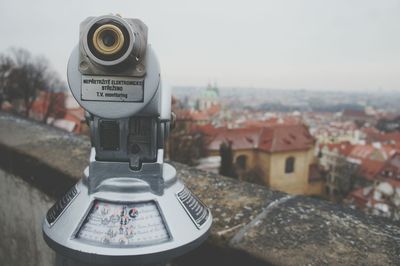 Close-up of coin-operated binoculars against cityscape