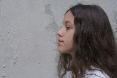 Close-up portrait of a young woman against wall
