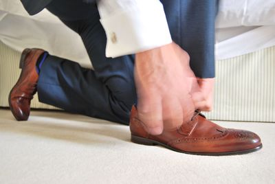 Low section of man tying shoelace at home