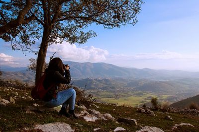 Man photographing mountains against sky