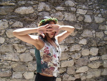 Young woman standing against stone wall