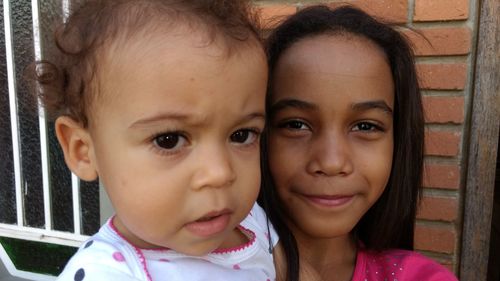 Close-up portrait of siblings against wall