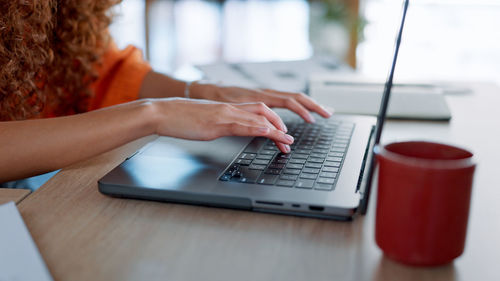 Midsection of woman using laptop at table