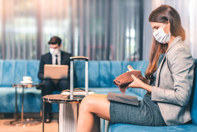 Young woman using mobile phone while sitting on table