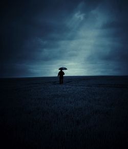 Person standing on field against cloudy sky