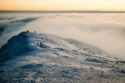 Scenic view of snow covered mountain by cloudscape against sky during sunset