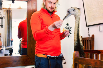 Man feeding ostrich at home