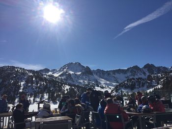 People at cafe against snowcapped mountains