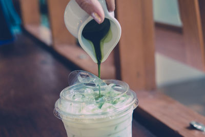 Cropped hand preparing drink on table