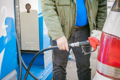 Midsection of man filling fuel in car tank