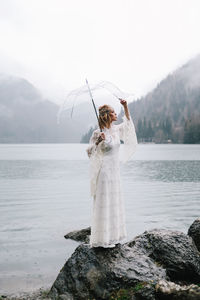 A tender sensual young woman bride in a fashionable wedding dress is standing in the rain in nature