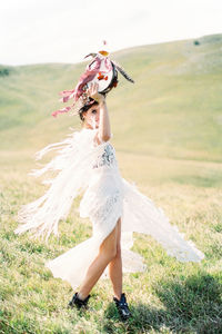 Full length of woman holding tambourine while walking on field