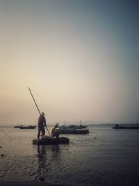 Men in boat on sea against clear sky