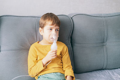  boy sits with an inhalation mask during cough and bronchitis. treatment with an inhaler at home