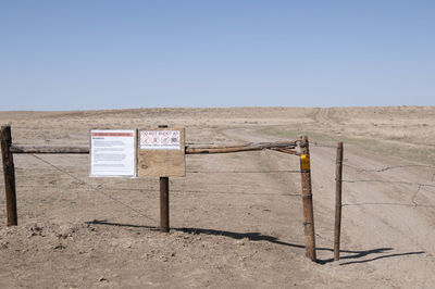 Information sign on field against clear sky