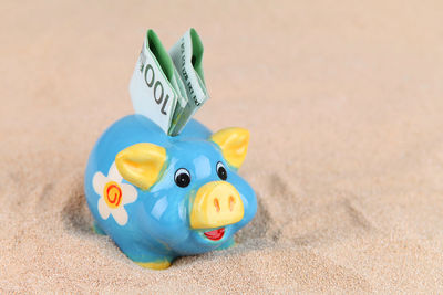 Close-up of paper currency in piggy bank on sand