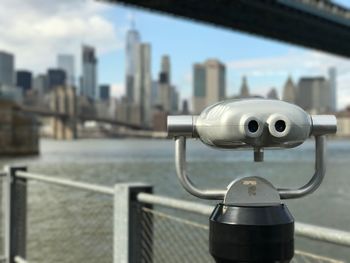 Close-up of coin-operated binoculars against cityscape