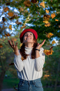 Girl in a red beret offers a dry autumn leaf.