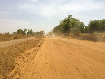 Dirt road passing through landscape against sky