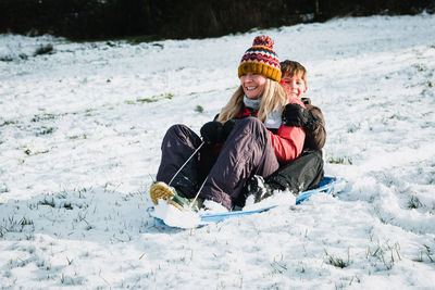 Rear view of woman sitting on snow covered field