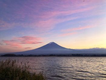 Scenic view of lake by mountains against sky during sunset