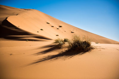 Scenic view of desert against clear blue sky