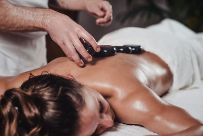 Midsection of therapist putting stones on woman at health spa