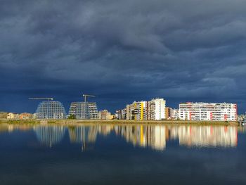 Buildings by river against sky in city